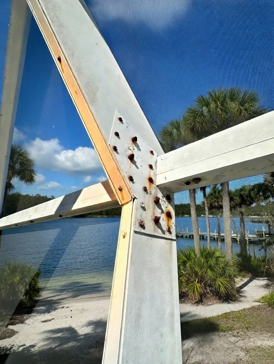 Rusted pool cage screws at an aluminum frame joint